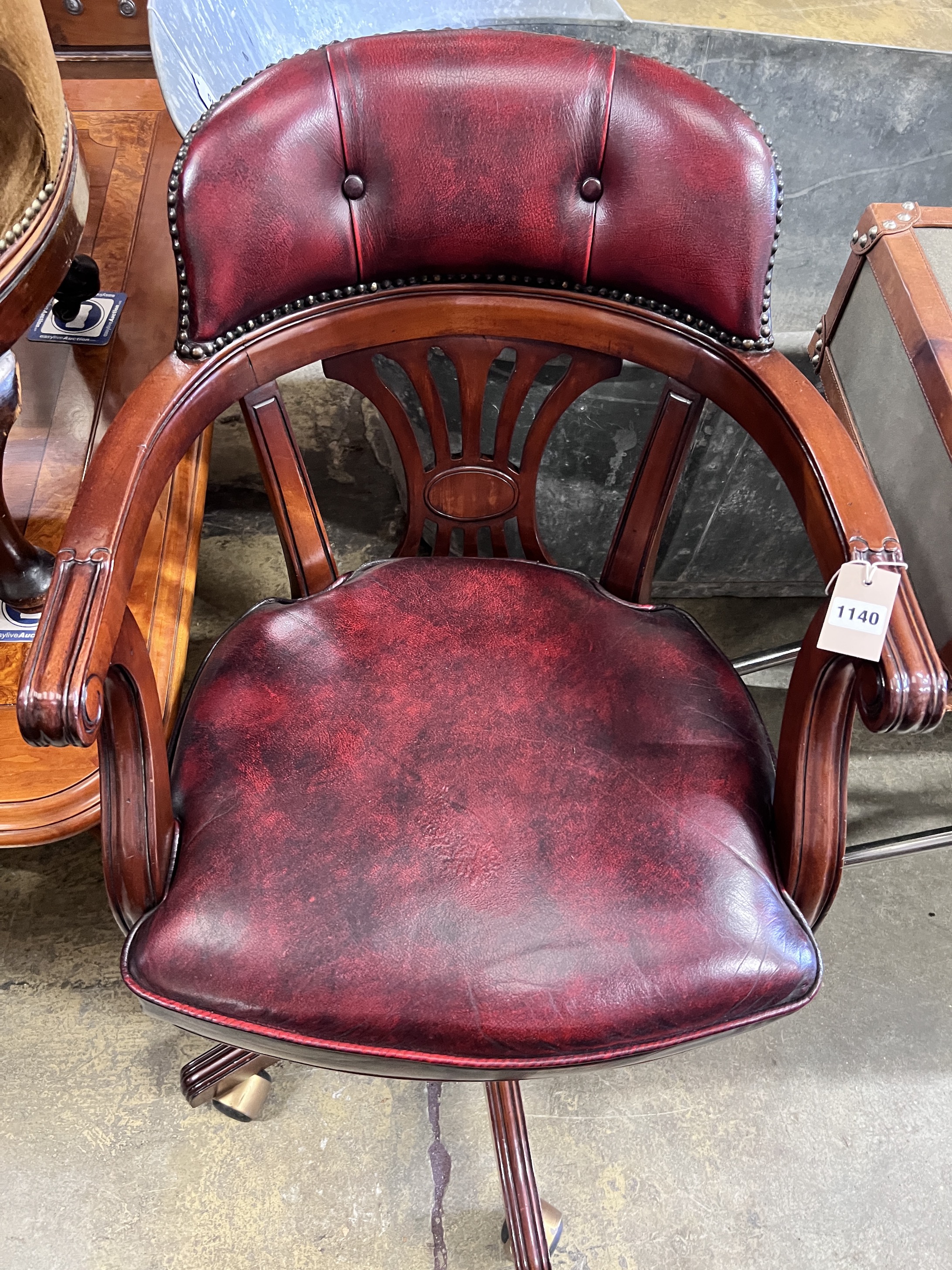 A modern mahogany revolving desk chair with leatherette upholstery, width 54cm